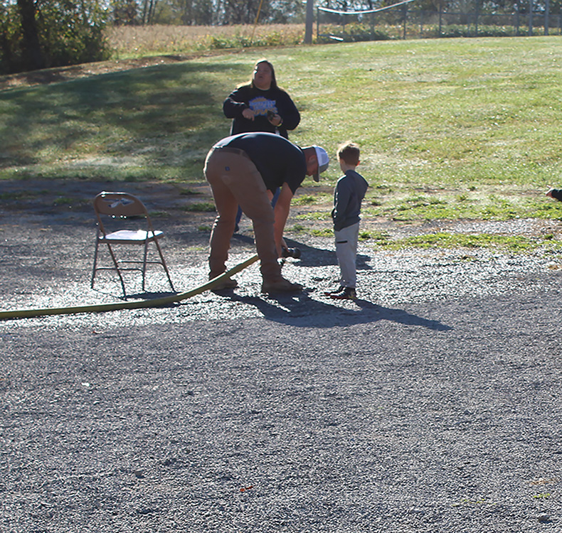 Fire Fighter Andrew Russell helps students with the fire hose