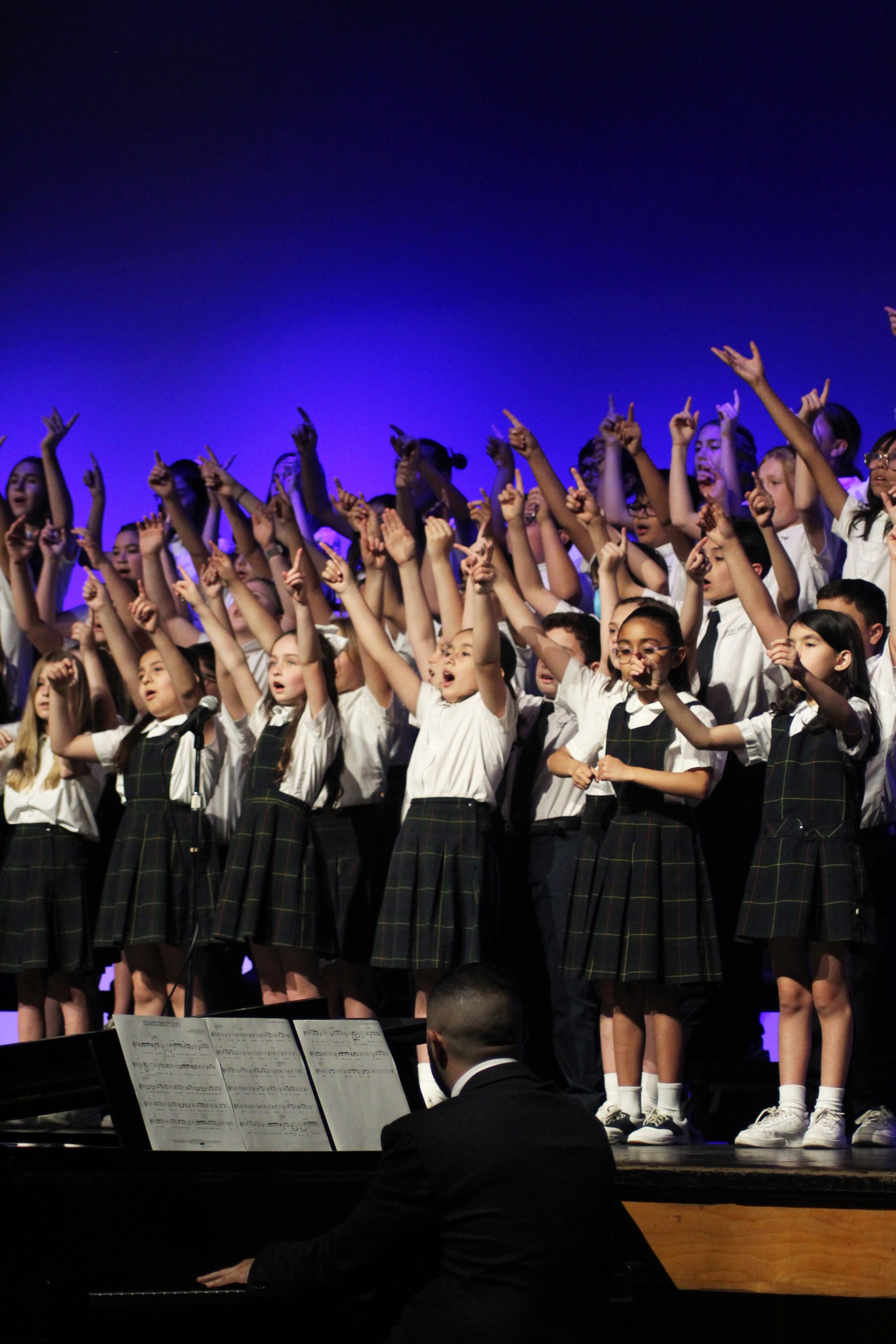 singing students with arms raised