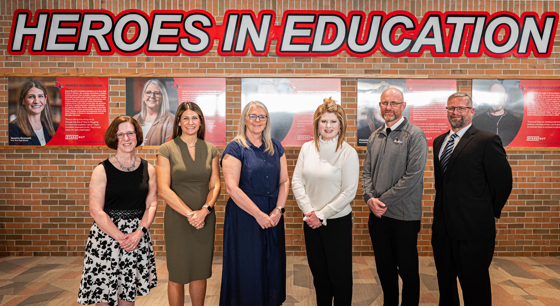 Jessica Brunsell stands with 5 other educators in front of a Heroes in Education display