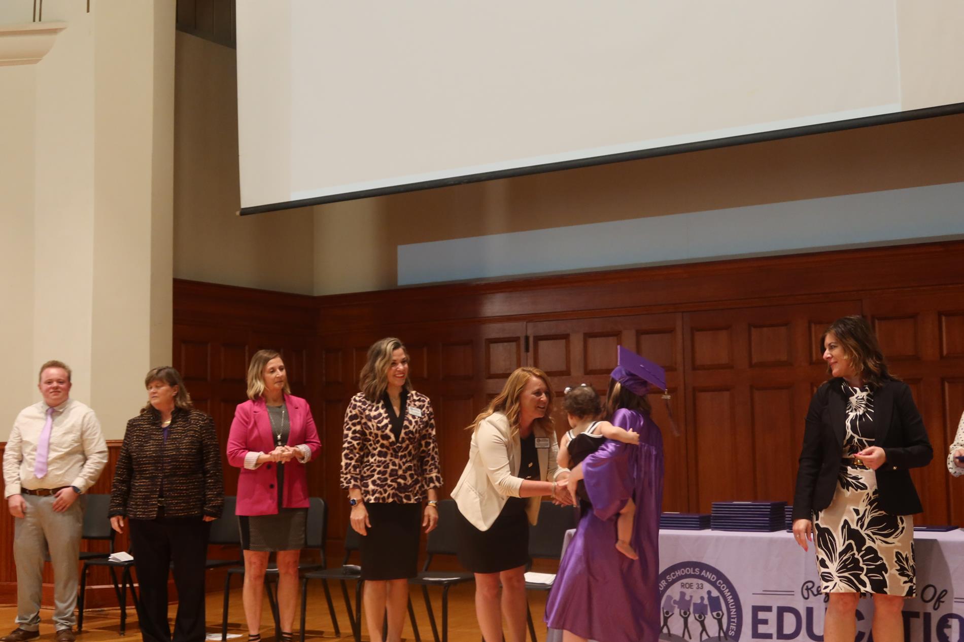 Kathryn Jennings greets a graduate walking the stage with their daughter