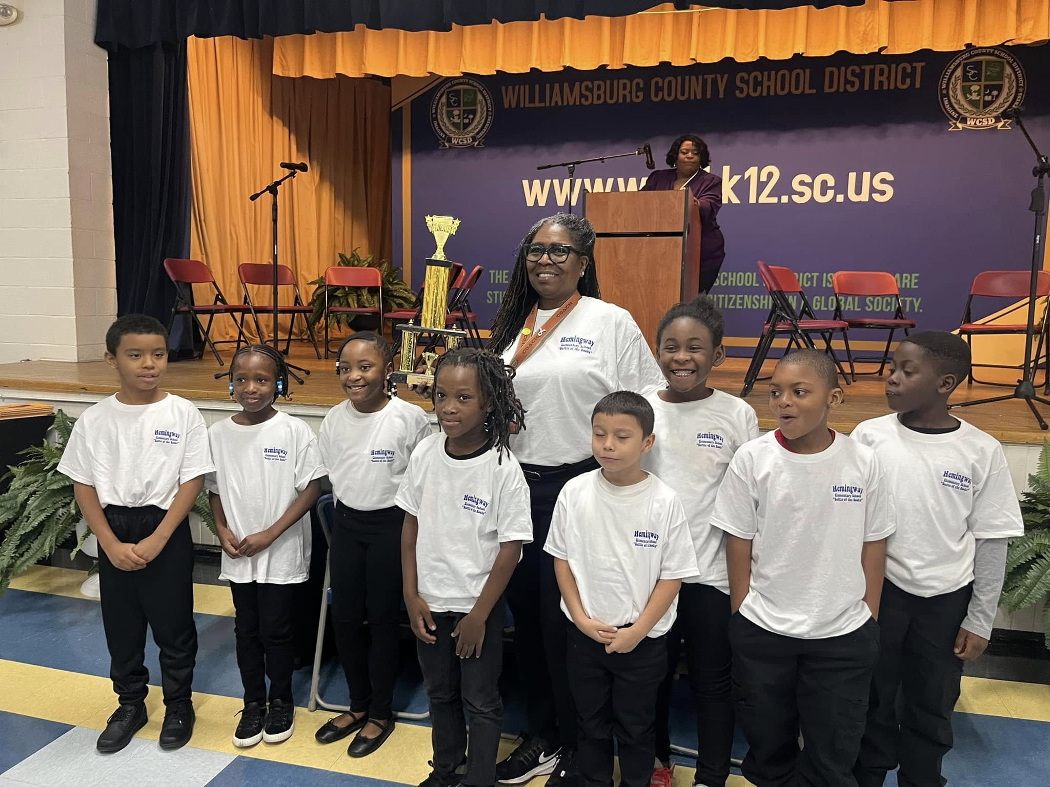 lady along with students standing in front of stage