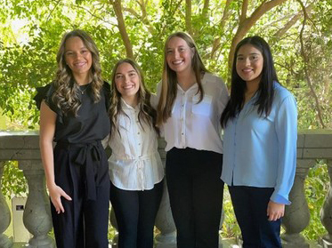 4 female LHHS students stand together while attending the DECA State Competition