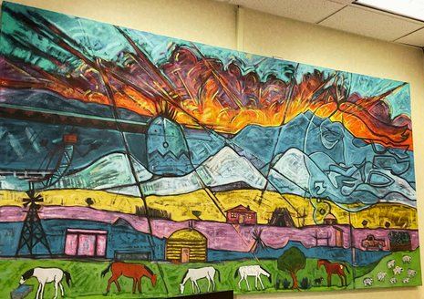 A student-painted mural of the Navajo homeland with hogans and livestock