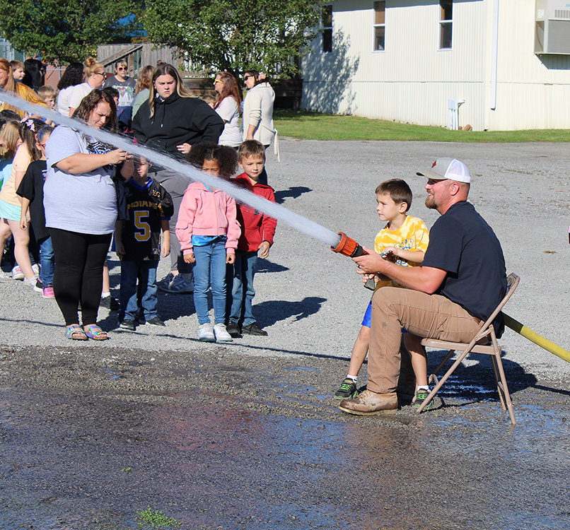 Fire Fighter Andrew Russell helps students with the fire hose