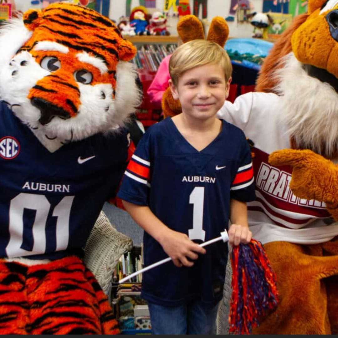 Toxey Dorsett in Auburn jersey standing between Aubie and Champ, the Prattville High School Lion Mascot