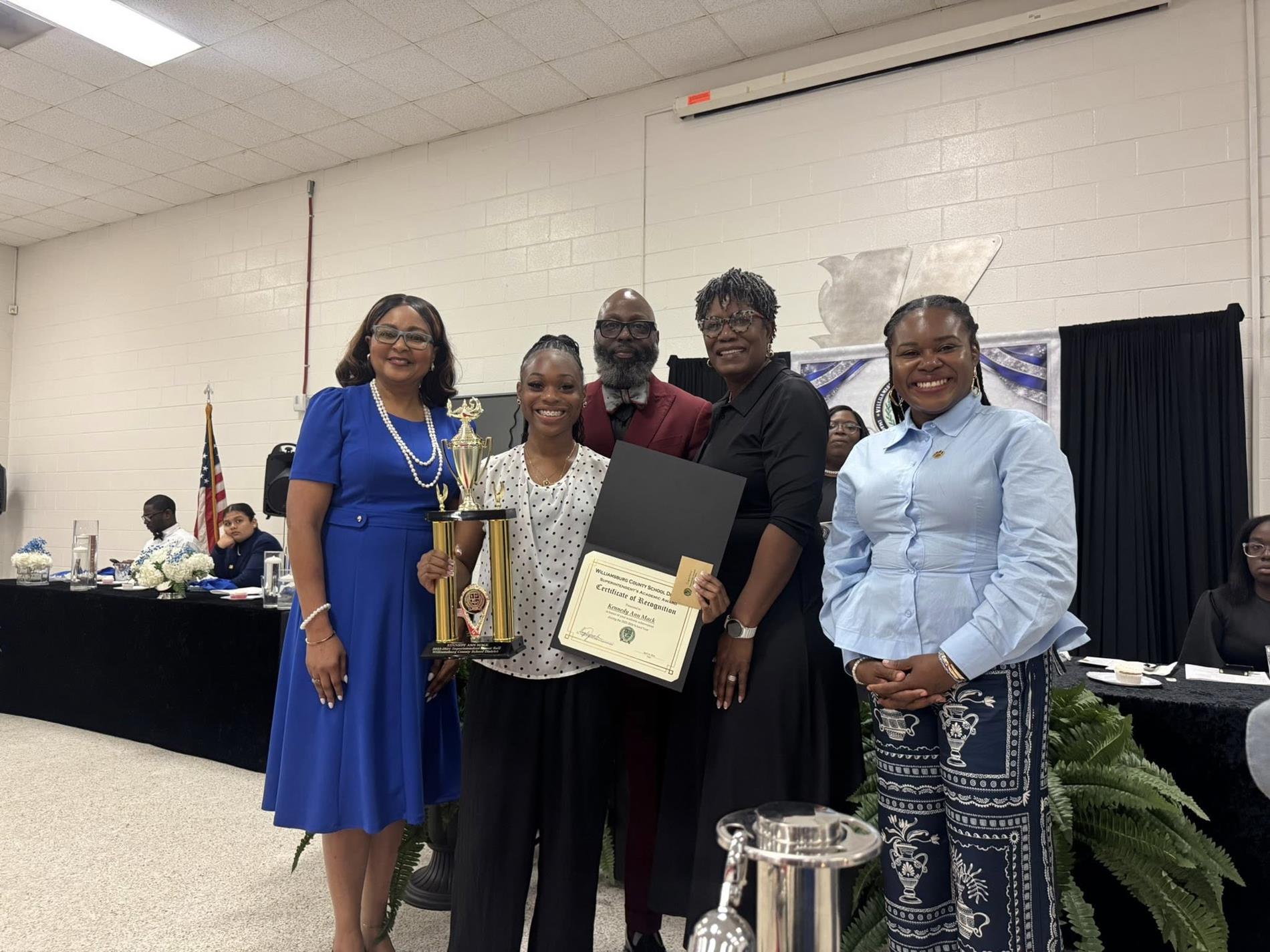 people standing together. one is receiving an award 