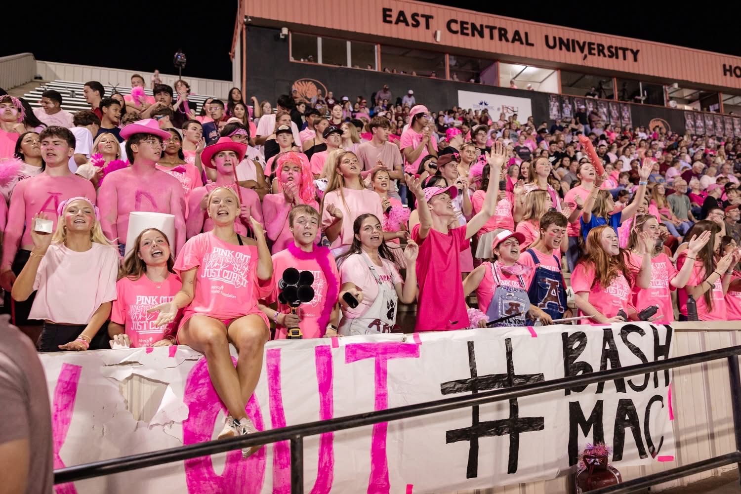 Students dressed in pink sit in the Student Cheer section at a football game.  Students dressed in pink sit in the Student Cheer section at a football game.