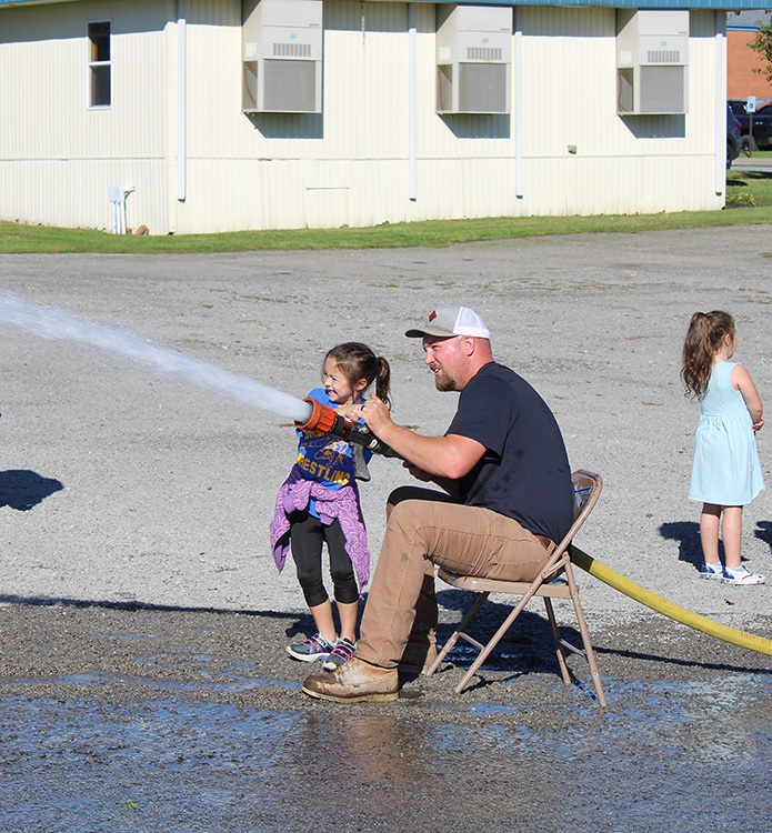 Fire Fighter Andrew Russell helps students with the fire hose