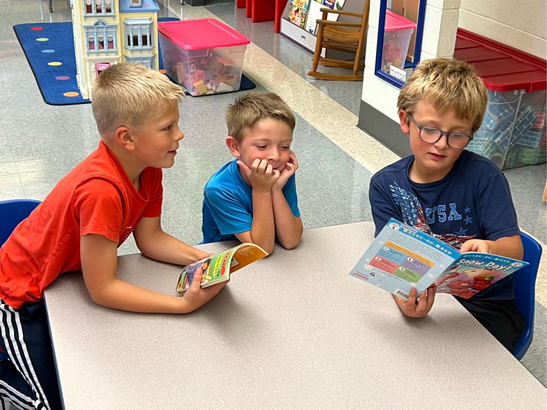 2nd grade boy reading to two preschool children