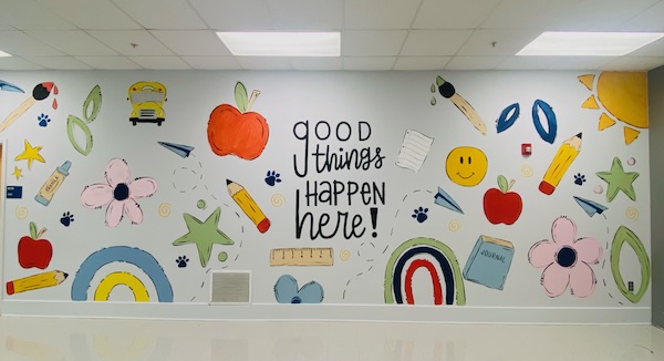 Mural in front lobby with school designs that says "Good things happen here"