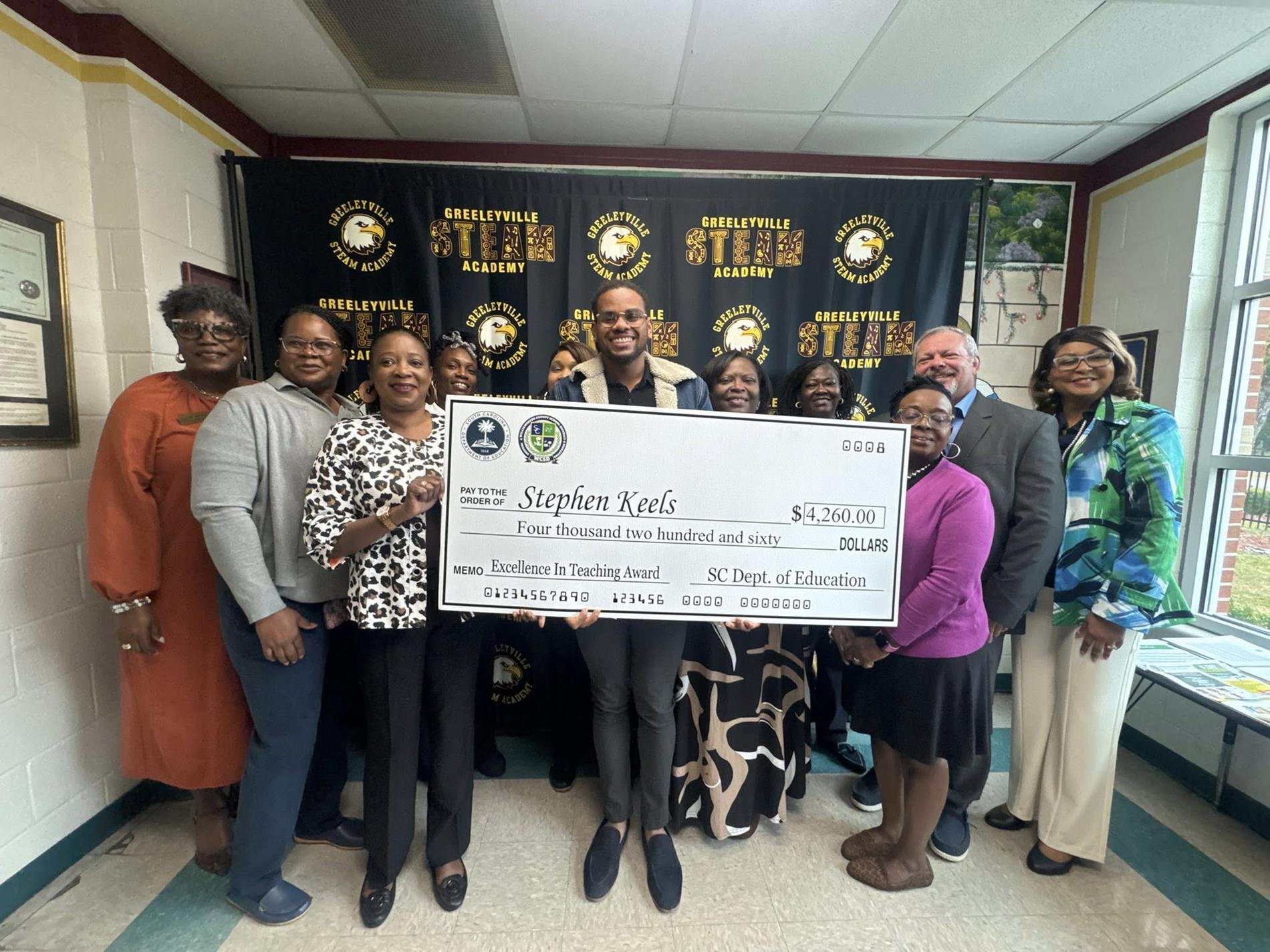 people standing in hall way holding a large check 