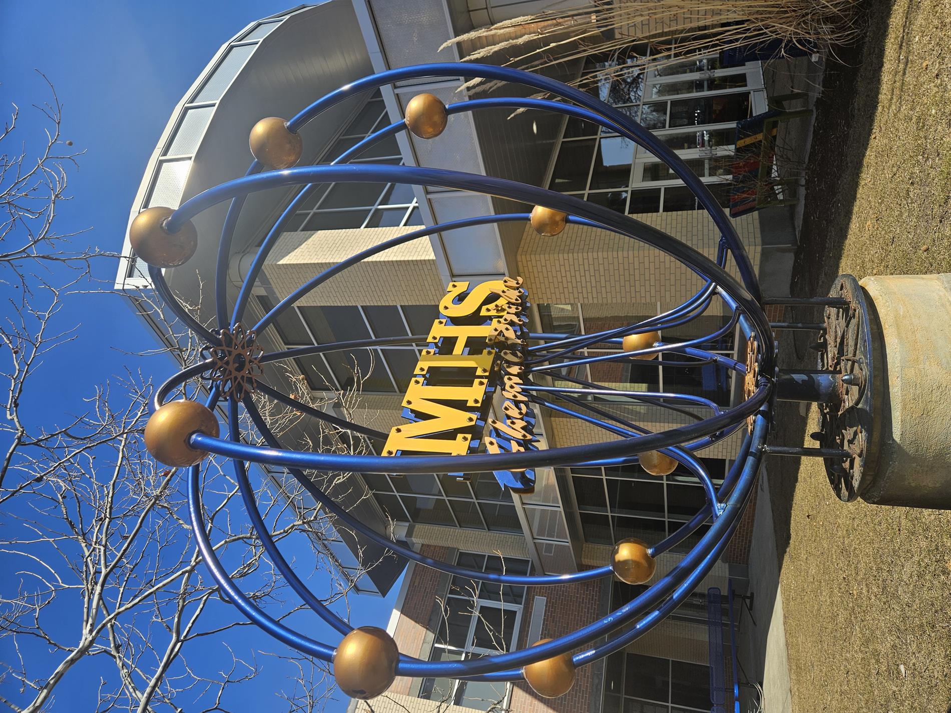 The exterior of Midland High School featuring the Midland Chemic atom sculpture in blue and yellow.