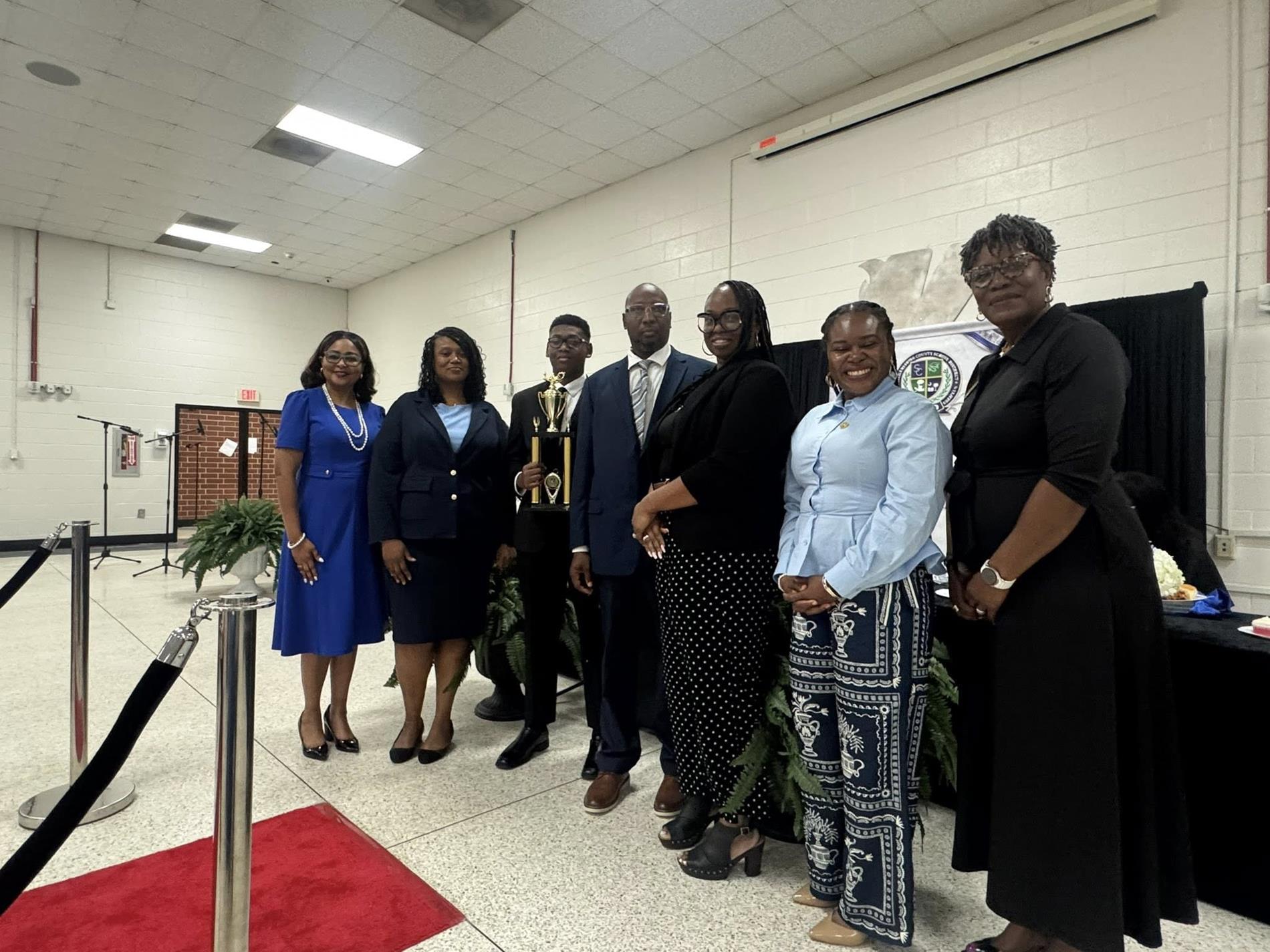 people standing together. one is receiving an award 