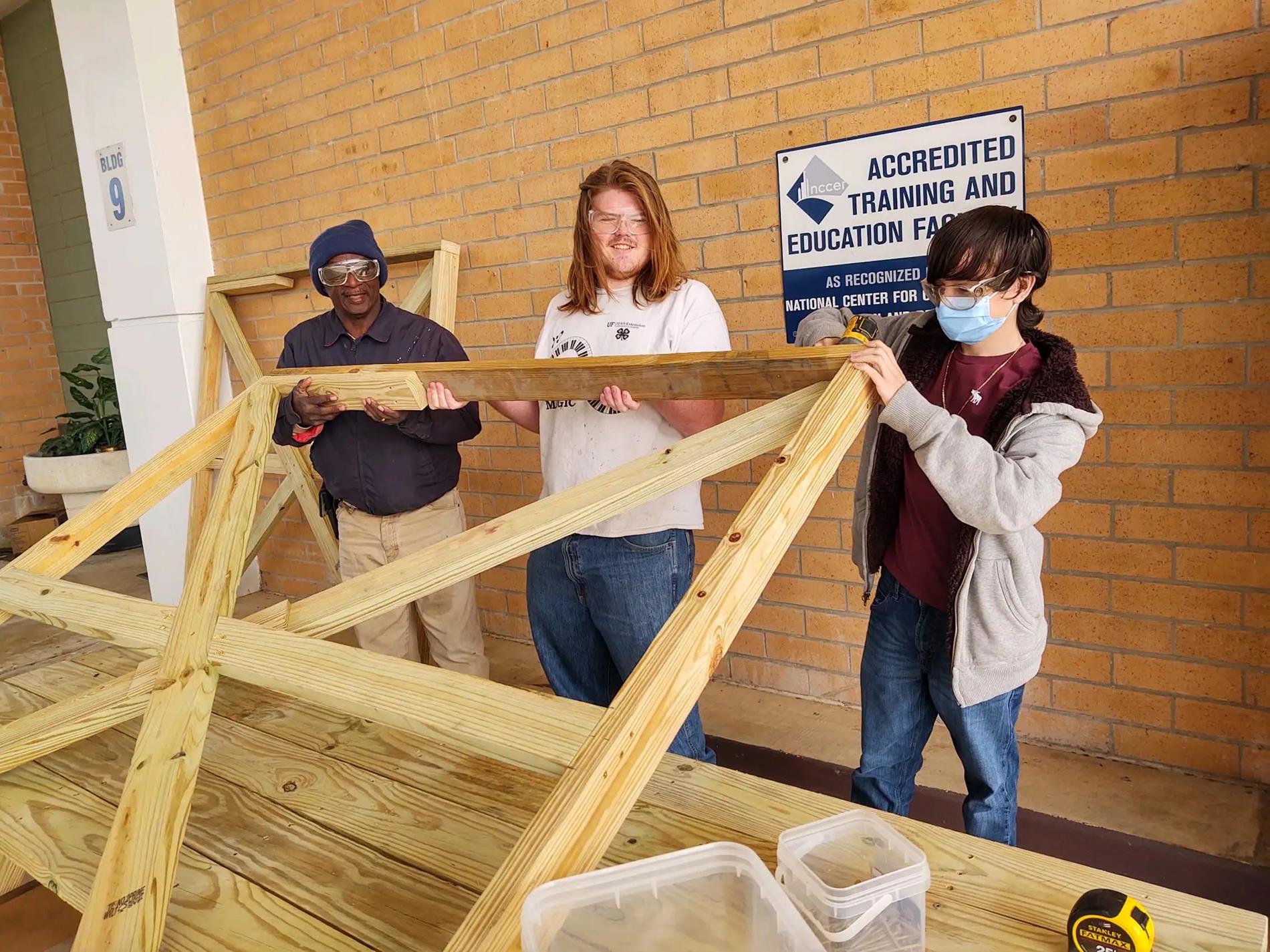 Students lifting a wood frame.