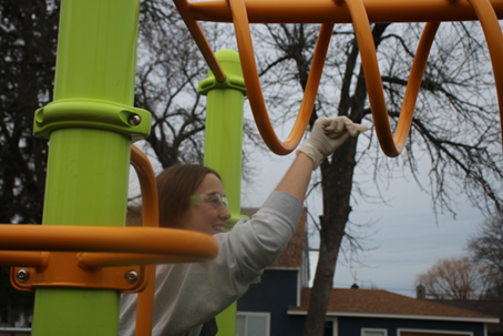 A student in protective lab clothing swabbing playground equipment