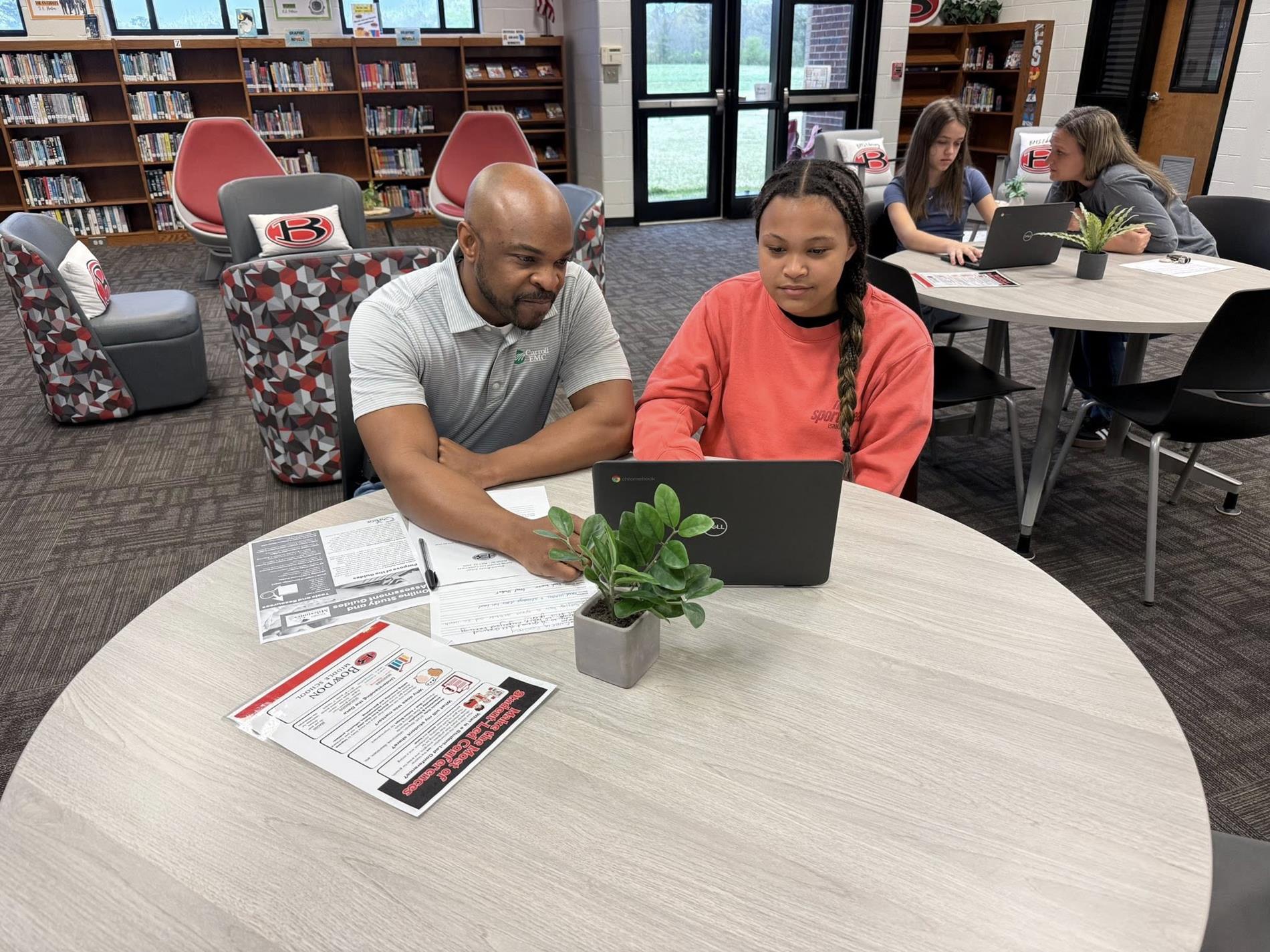 A student with her father in the library participating in student-led conferences
