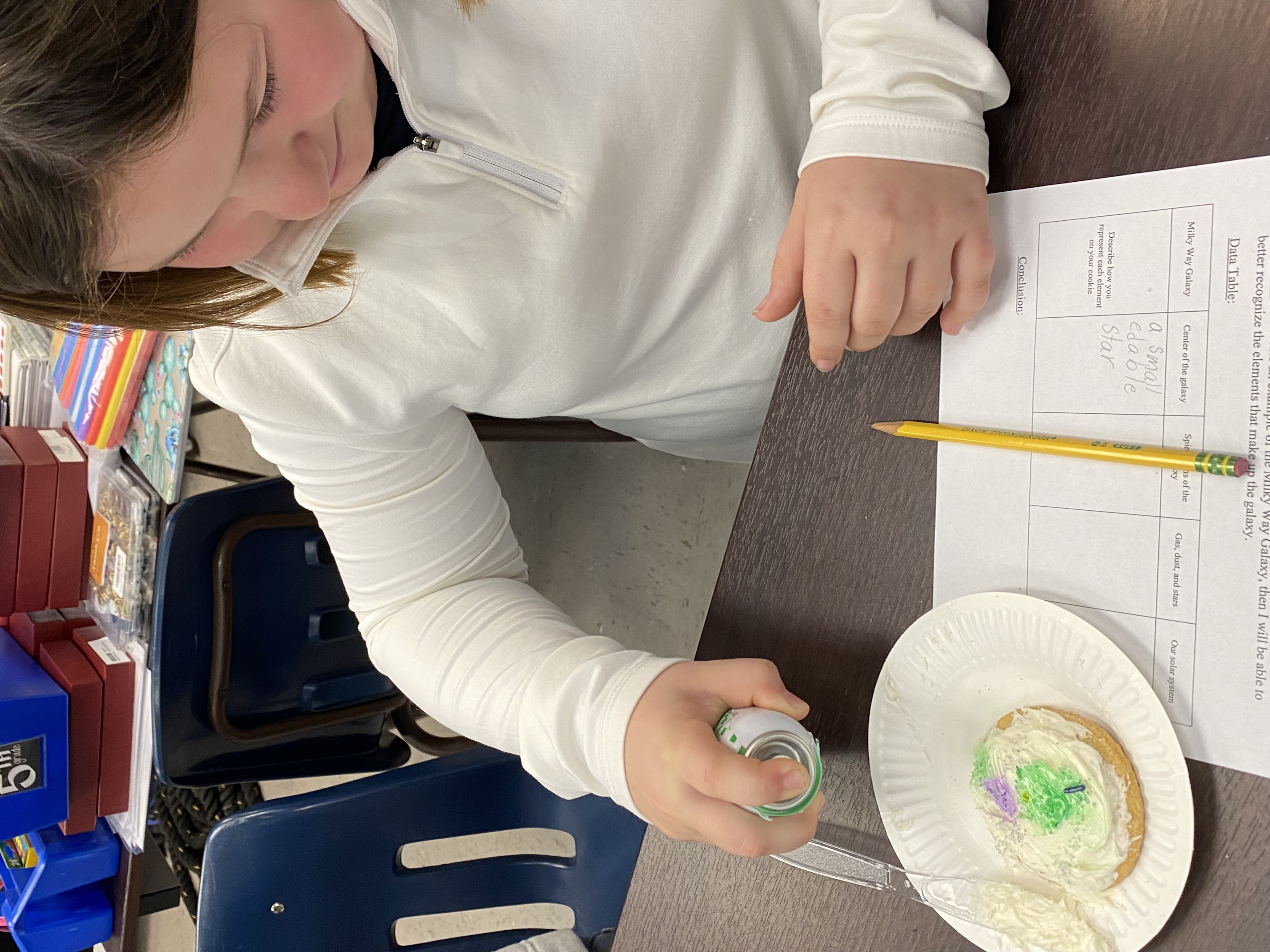 A student adding the gas to their galaxy cookie. 