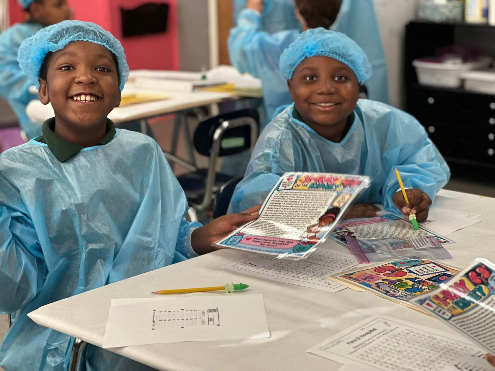 Two students in medical gowns smile while working with reading passages and review activities.