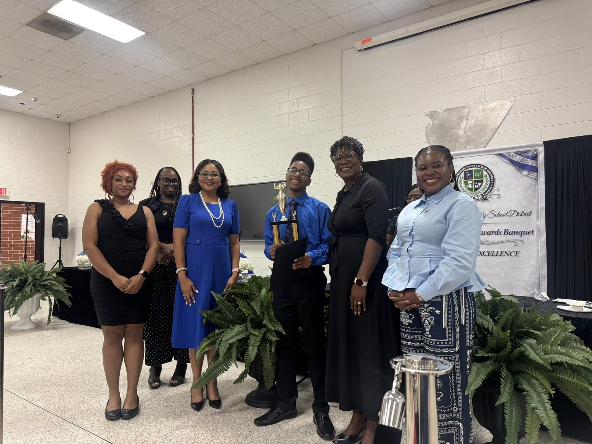 people standing together. one is receiving an award 