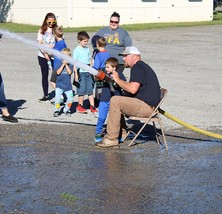 Fire Fighter Andrew Russell helps students with the fire hose