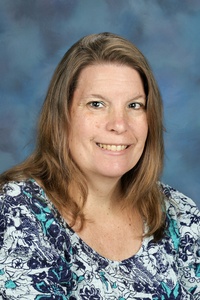 Teacher smiling against a blue background