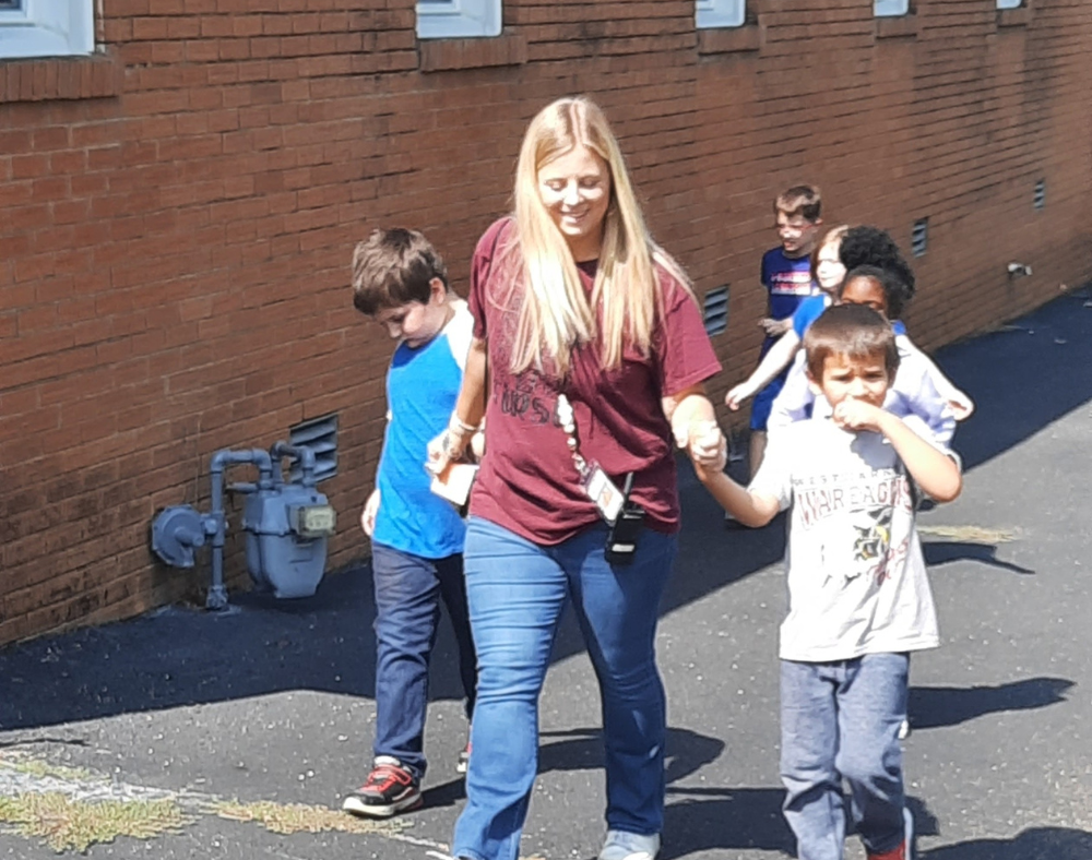 primary students with teacher playing outside