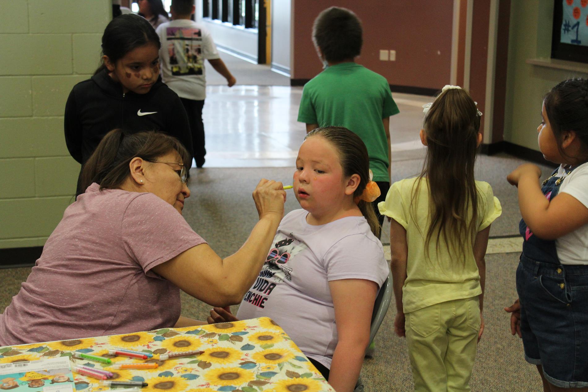 Staff face painting a student