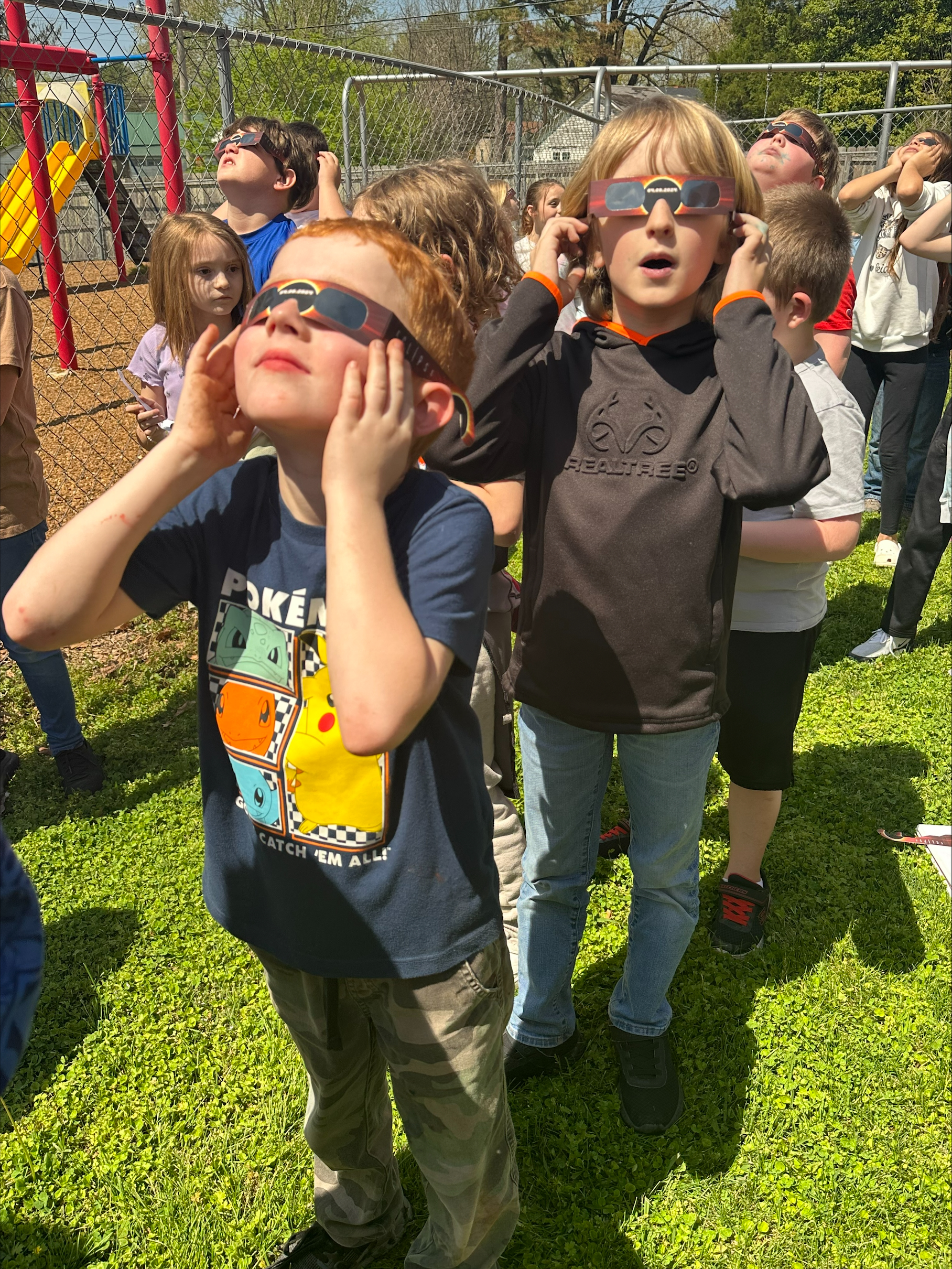Image of young students watching the solar eclipse with protective glasses