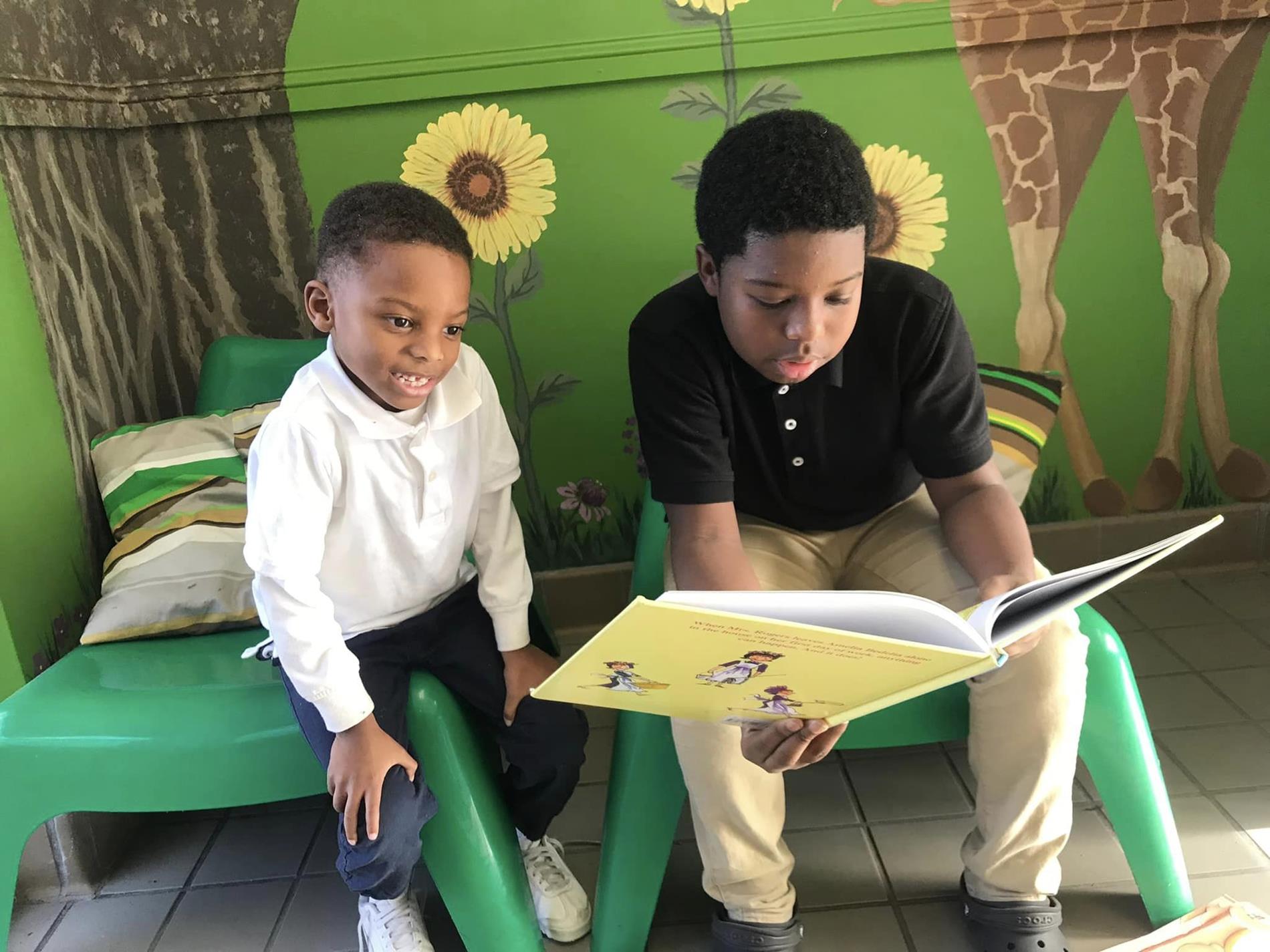 Sixth grade students reading to a Kindergarten student