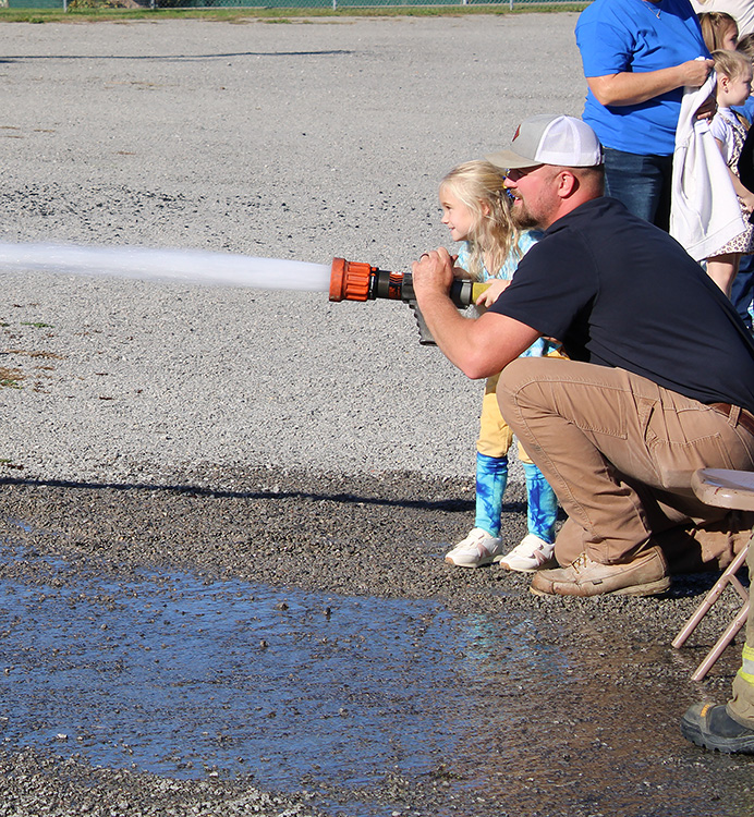 Fire Fighter Andrew Russell helps students with the fire hose