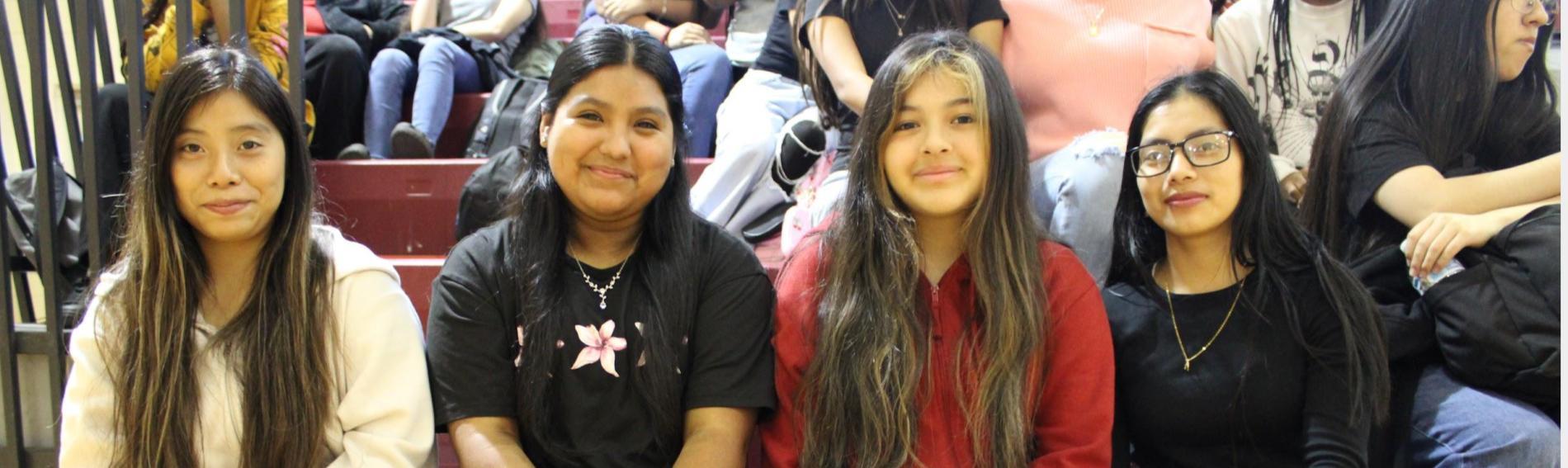 Four girls sit together on the bleachers