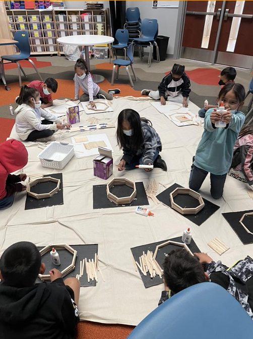 Students on the floor building frames together.