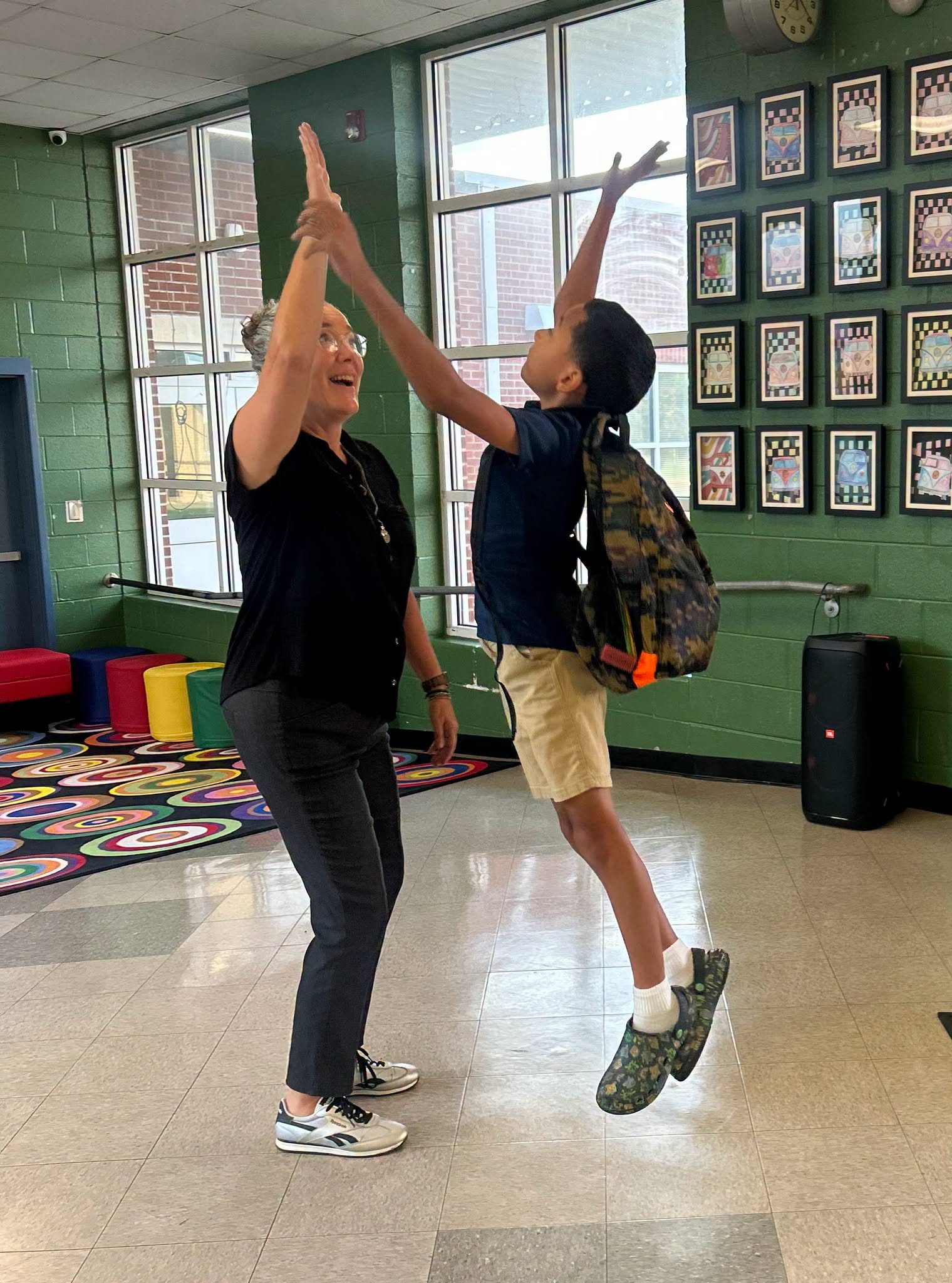 South Side Elementary staff member and student sharing an enthusiastic high-five in the school hallway.
