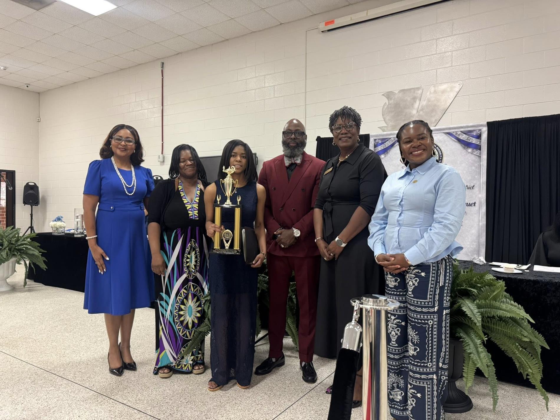 people standing together. one is receiving an award 