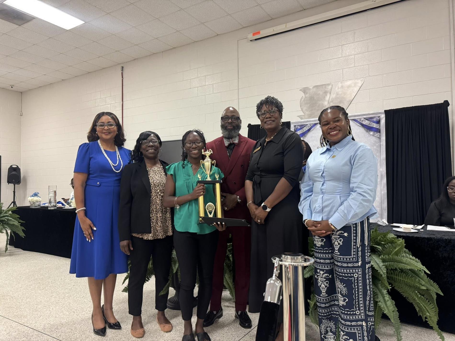 people standing together. one is receiving an award 