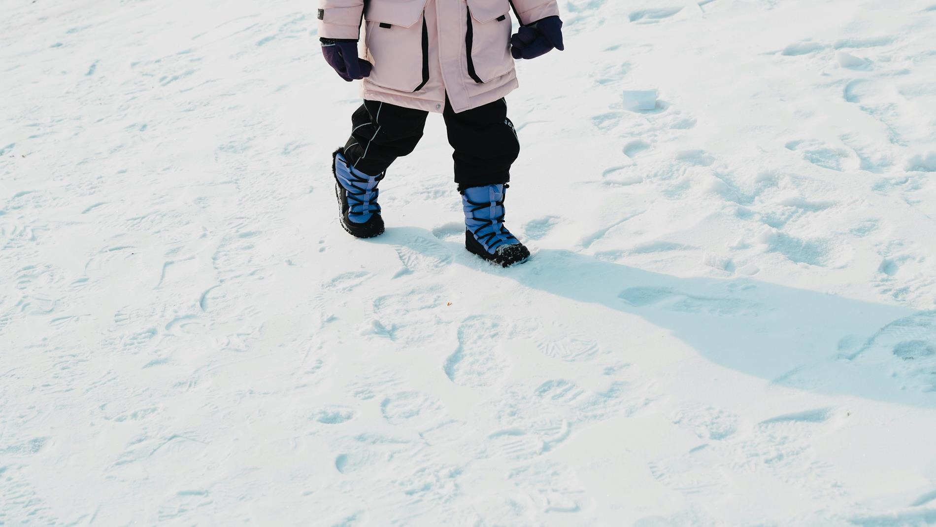 A young boy holds up a book and smiles in his elementary school building
