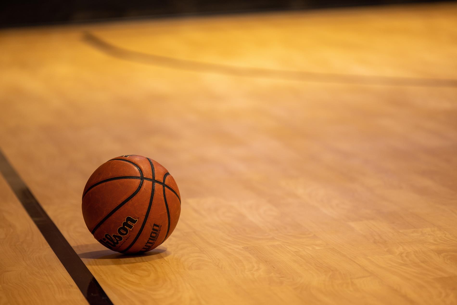 An orange Wilson basketball sits on a wooden basketball court
