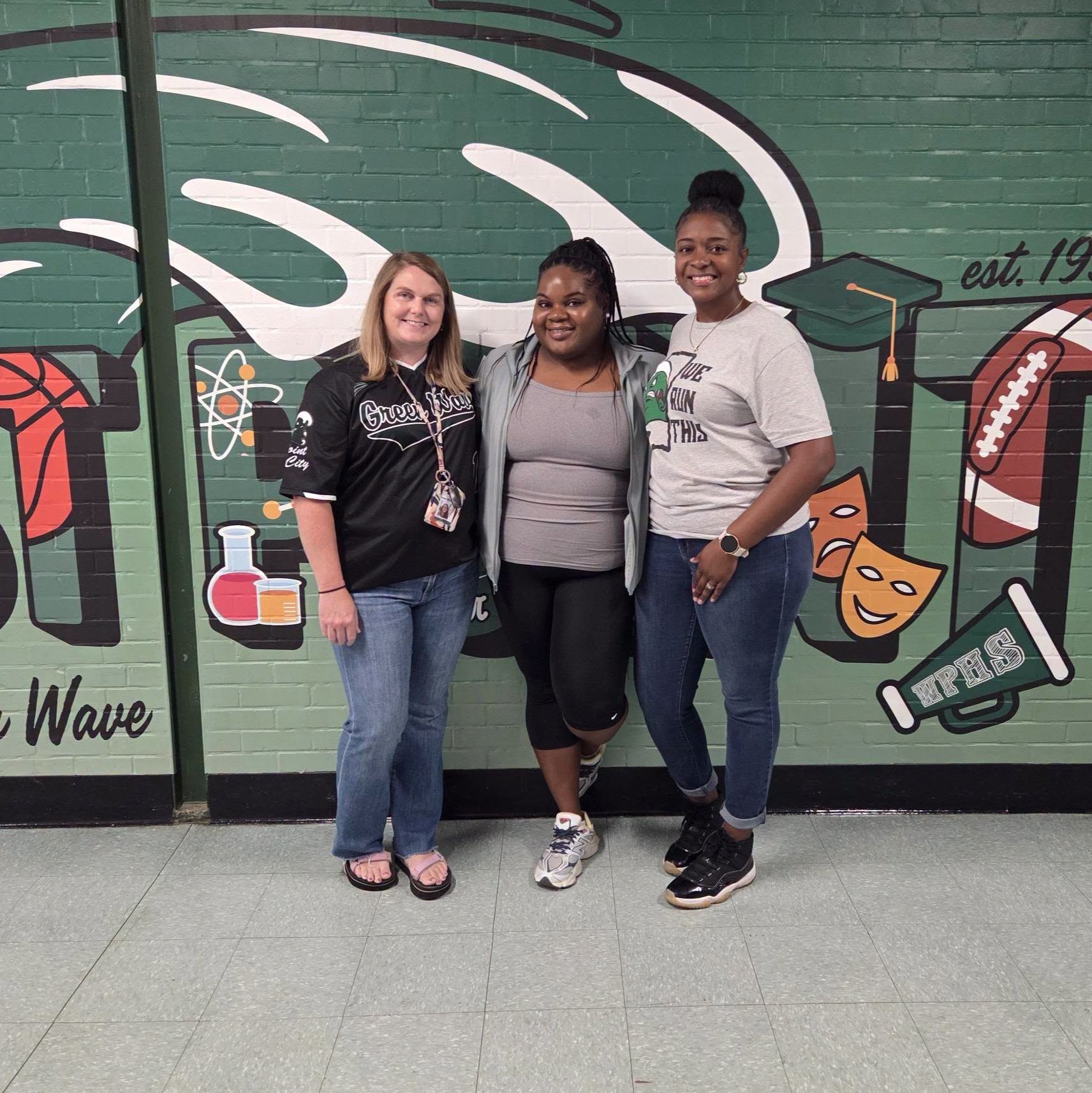 West Point staff members pose together in front of a school mural following the Bright Horizons partnership donation.