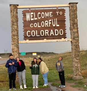 Students in front of the Welcome to Colorful Colorado sign