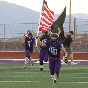 Football player running onto the field with an American Flag
