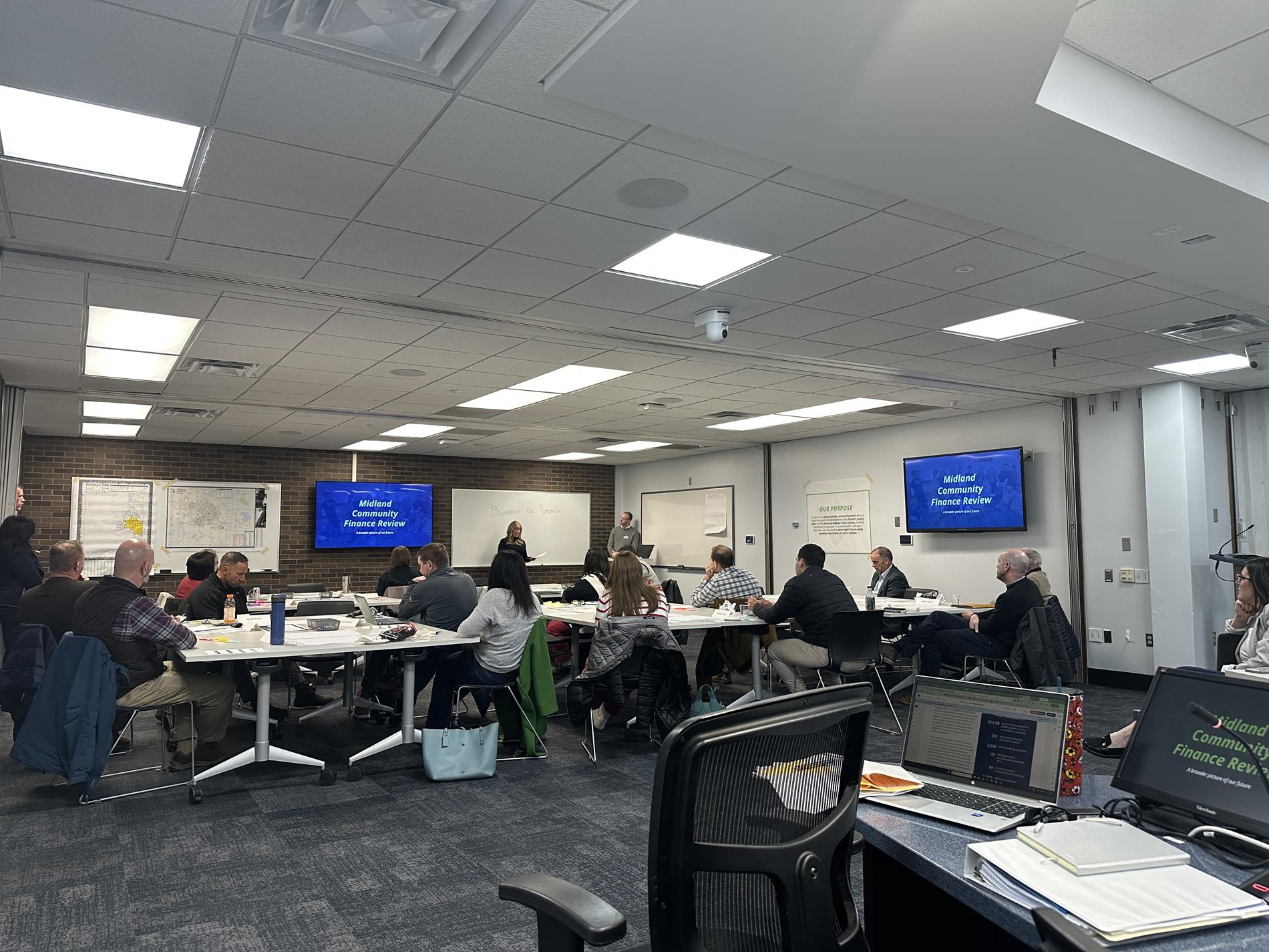 Steering Team members sit amongst tables in the Admin Center conference room