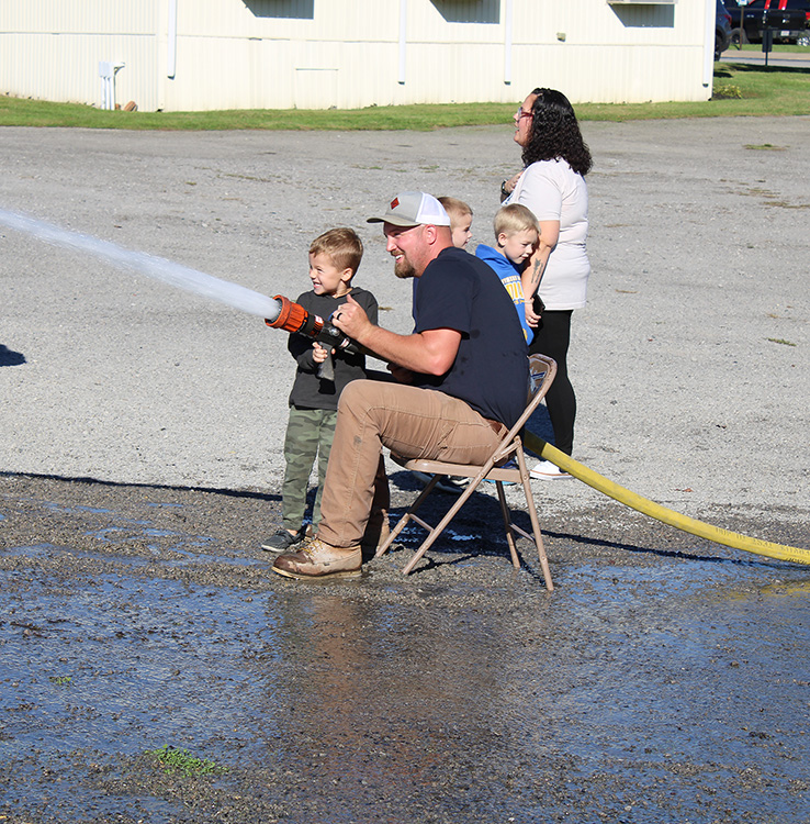 Fire Fighter Andrew Russell helps students with the fire hose