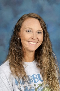 Teacher smiling against a blue background
