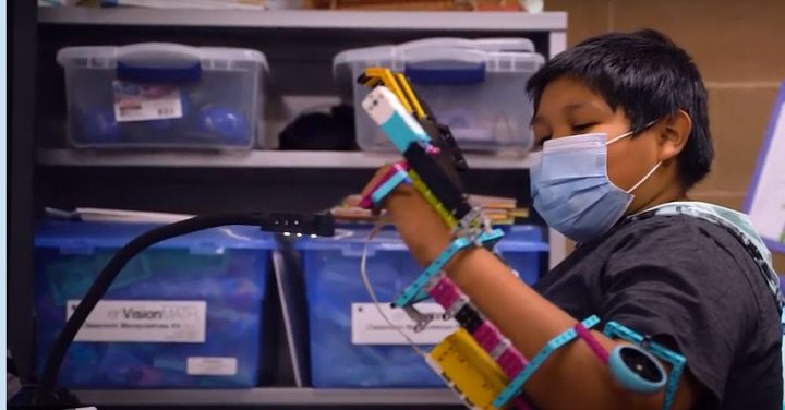A Little Singer student building a smart-motor robot at a classroom shelf.
