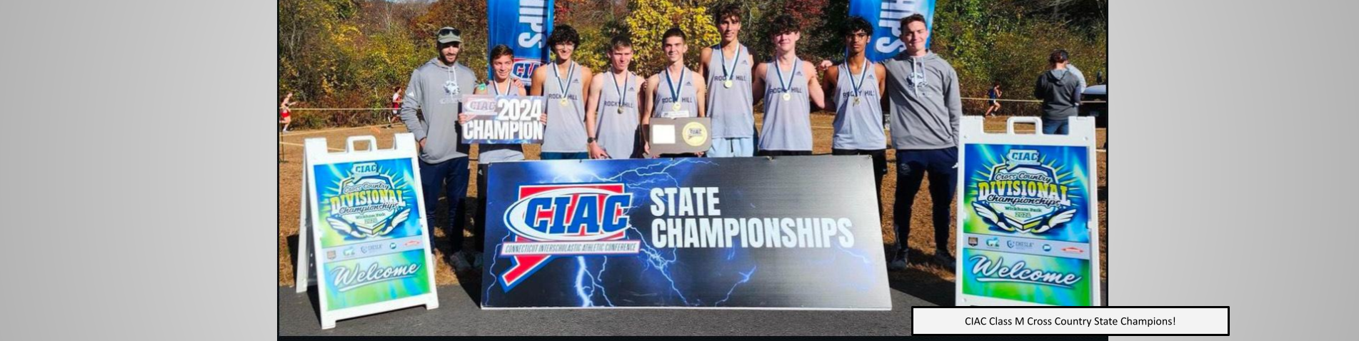 Boys Cross Country posing in from of the CIAC championship banner