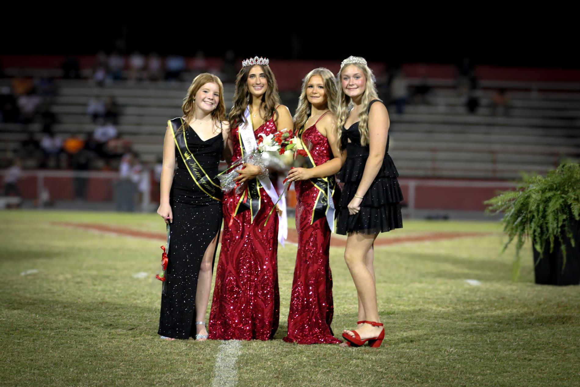 4 8th grade homecoming attendants in red and black dresses