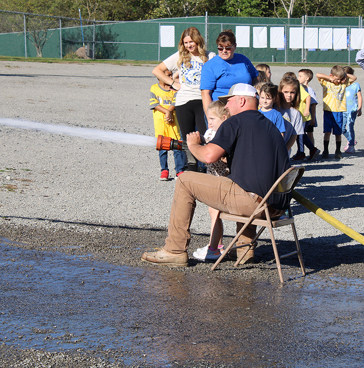 Fire Fighter Andrew Russell helps students with the fire hose