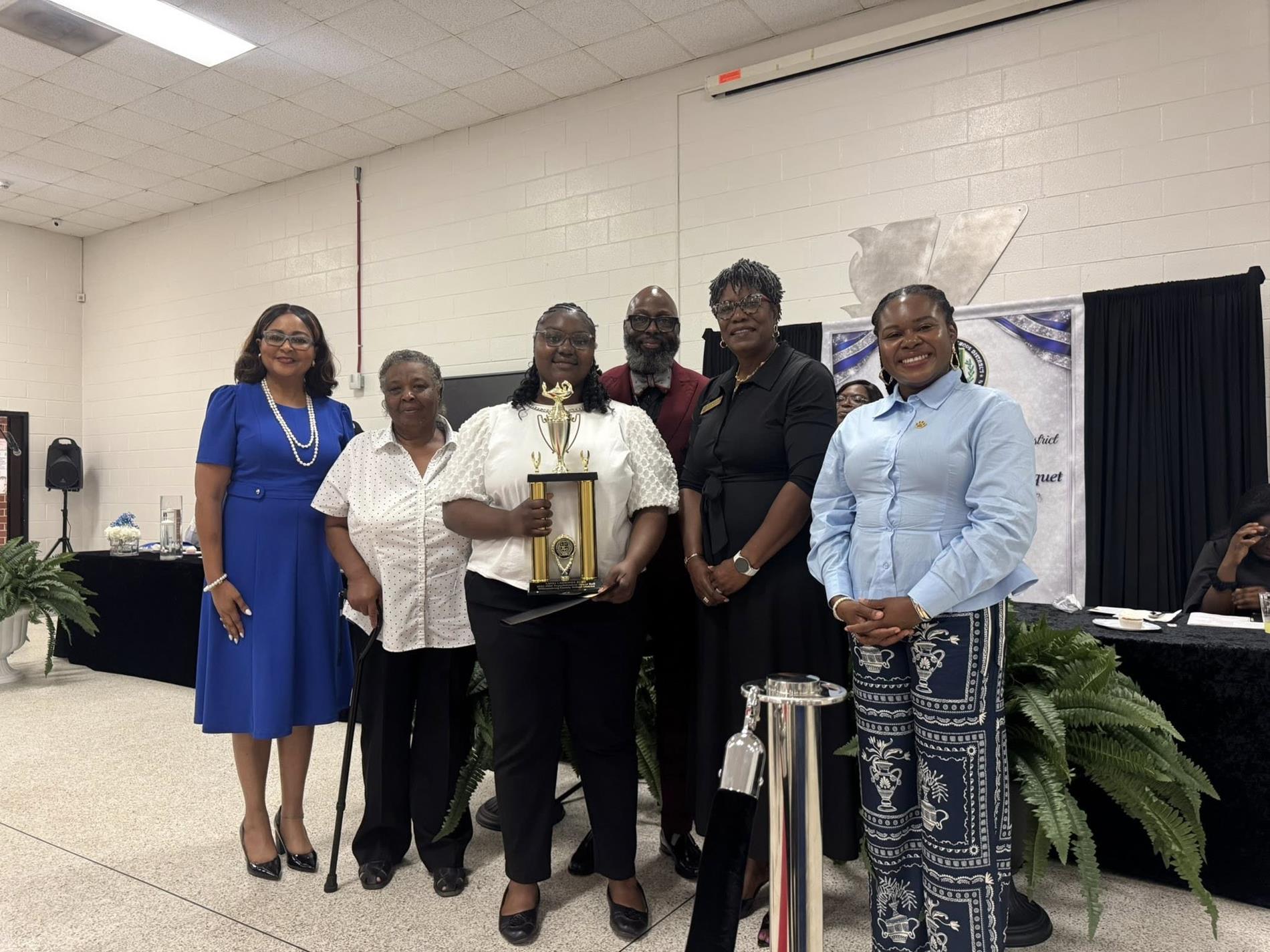 people standing together. one is receiving an award 