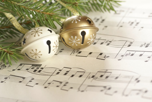 White and gold bells with an evergreen branch on a piece of sheet music.