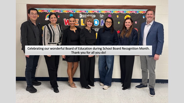 Members of the Demarest, NJ Board of Education standing in front of a bulletin board